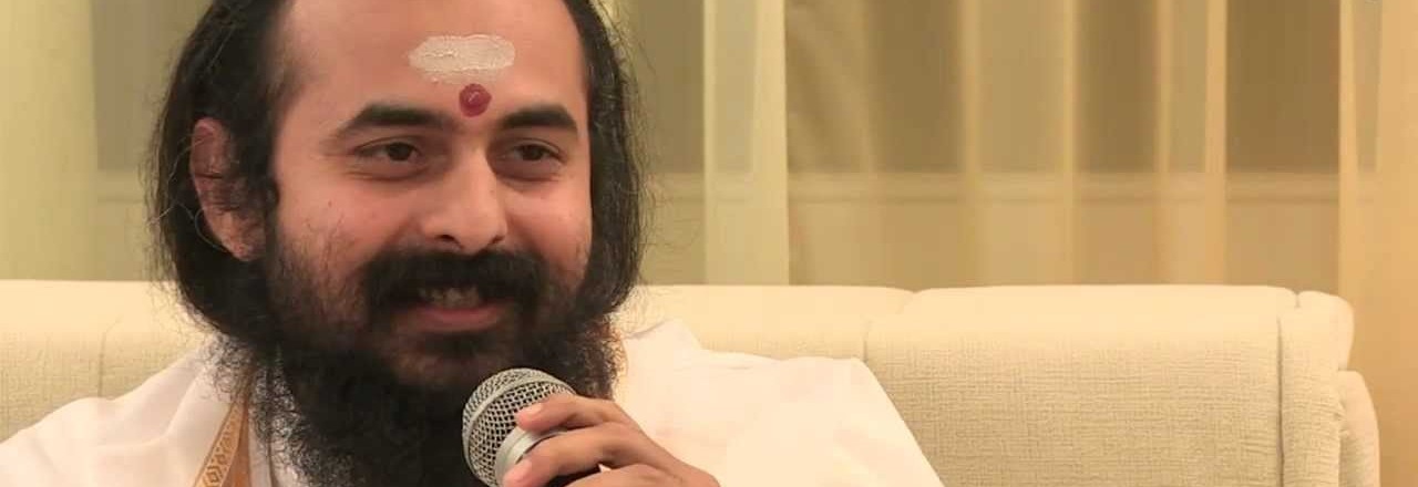 Swami Vaishampayan speaking into a handheld microphone